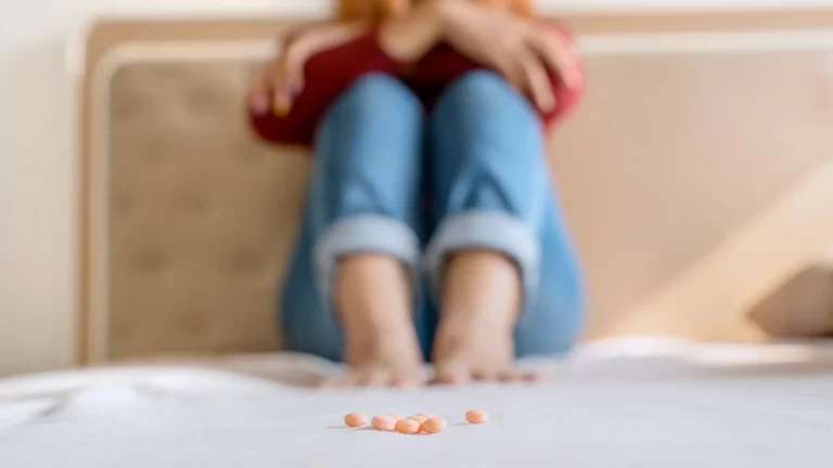 Person with pills on bed